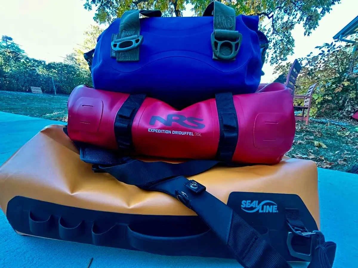 Color-coded waterproof dry bags organized with hiking gear and clothing for Great Walks packing