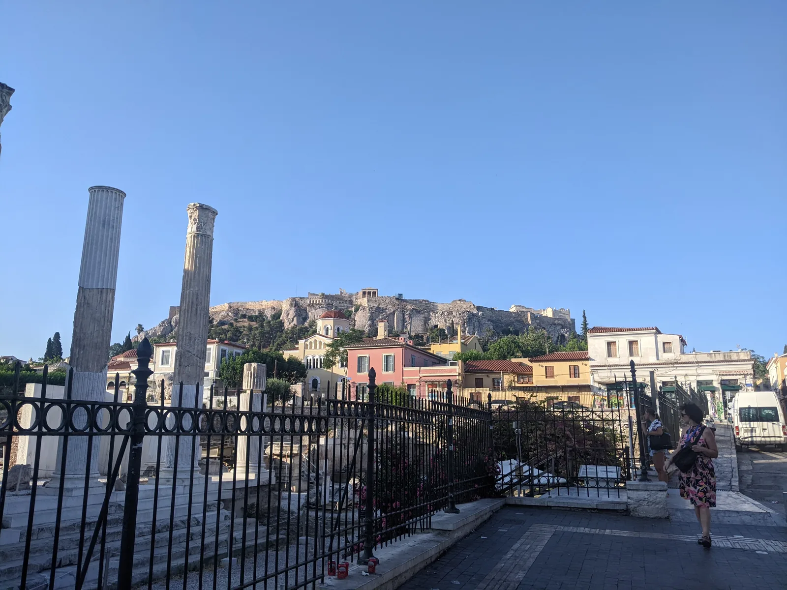Roman Agora ruins with standing columns and the Acropolis visible on the hill behind, Athens
