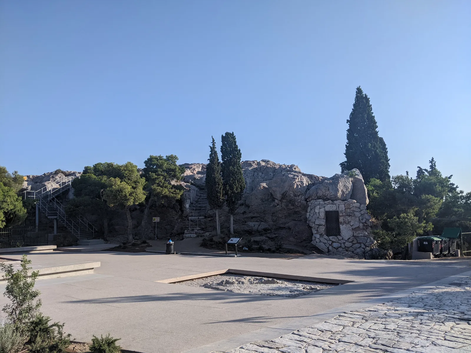 Ancient rock ruins near the Acropolis with cypresses and clear blue sky, Athens