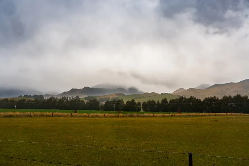 A field with a fence and mountains in the background