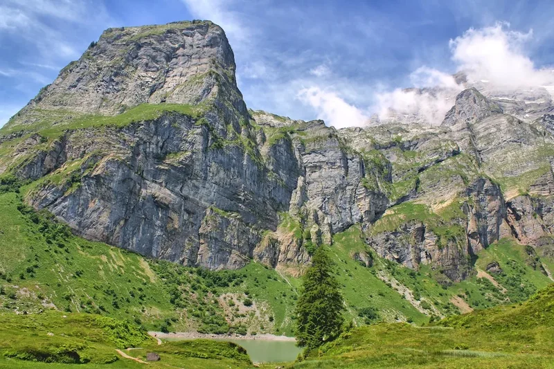 Majestic mountains dominate a verdant, sunny landscape.
