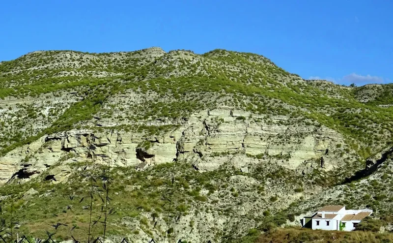 White house nestled on a rocky, green hillside