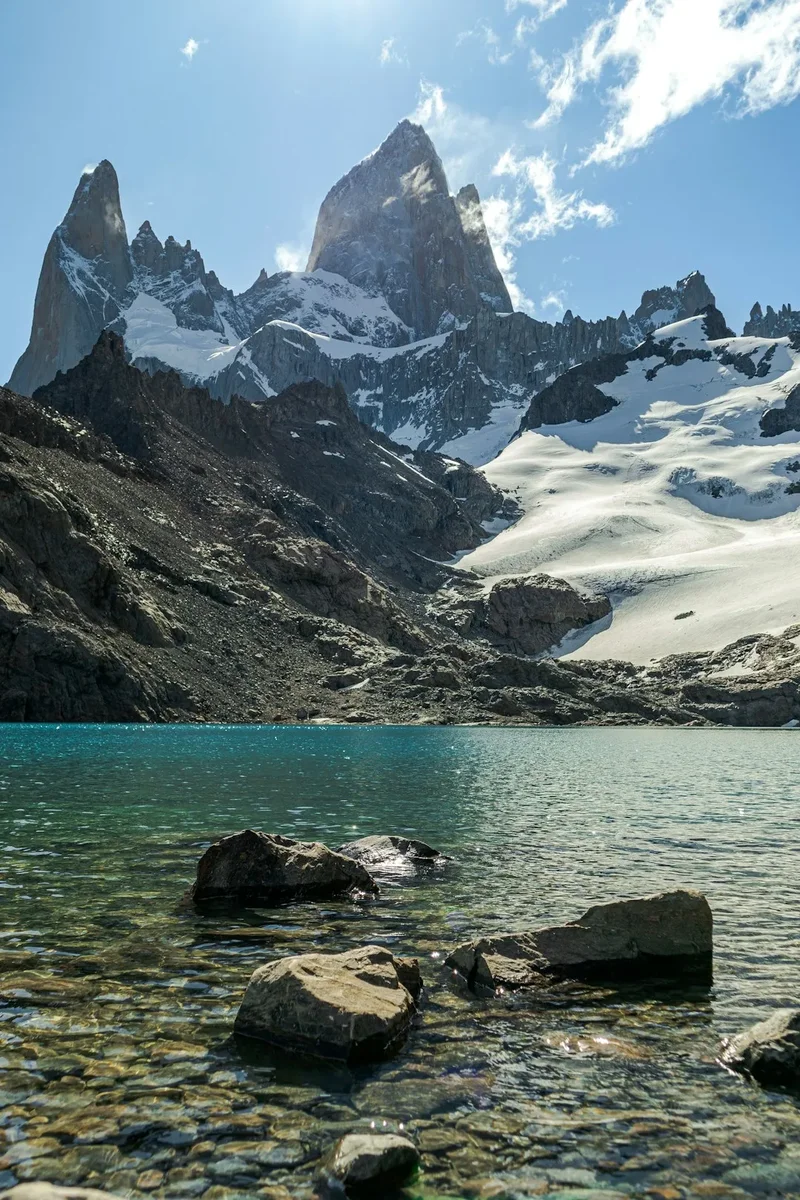 A lake surrounded by rocks and snow covered mountains