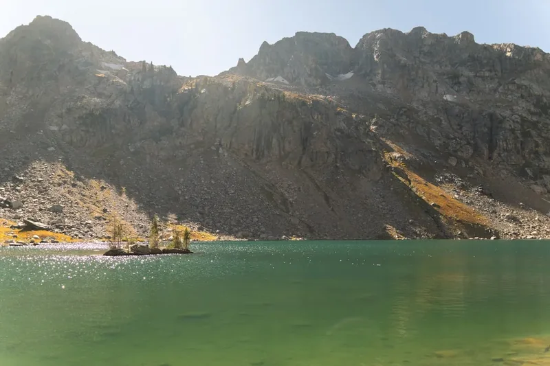 Green mountain lake with rocky slopes and small island