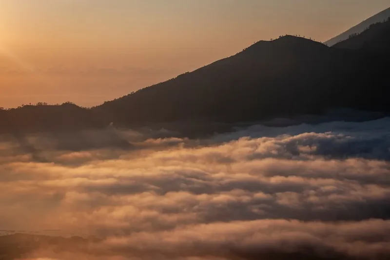 Golden sunrise over a sea of clouds and mountains.