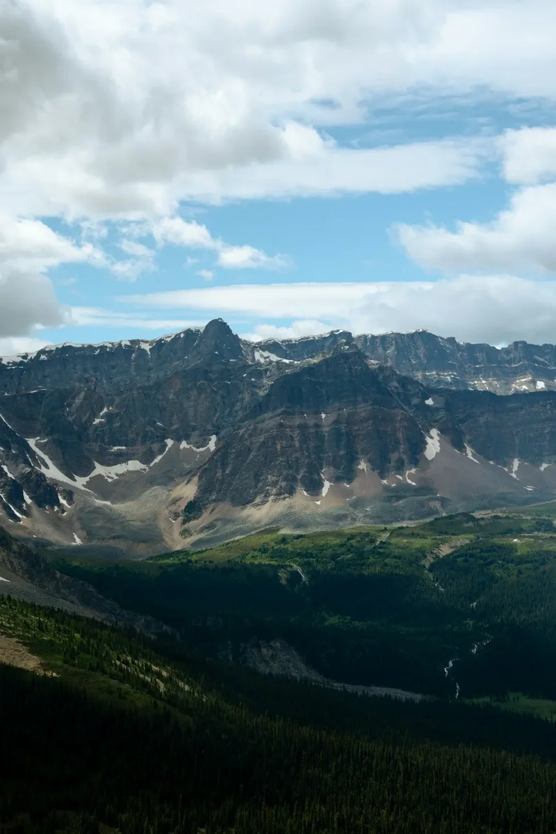 Majestic mountain range under a cloudy blue sky.