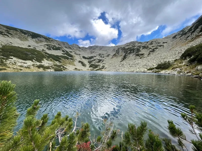 A lake surrounded by a mountain range under a cloudy sky