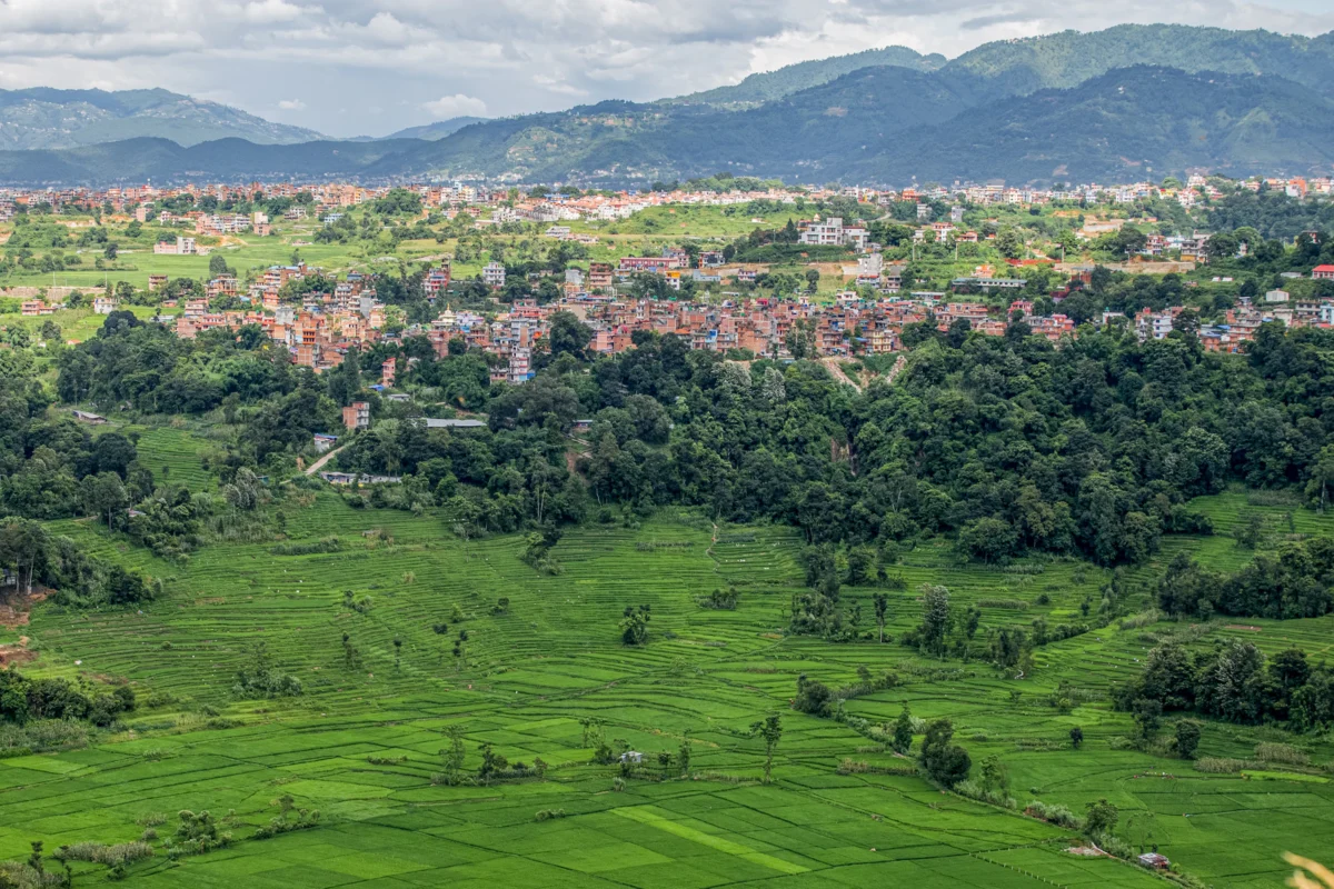 Green landscape with buildings and mountains in distance