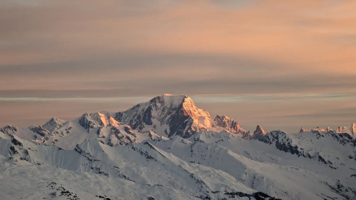 A snow covered mountain range under a cloudy sky