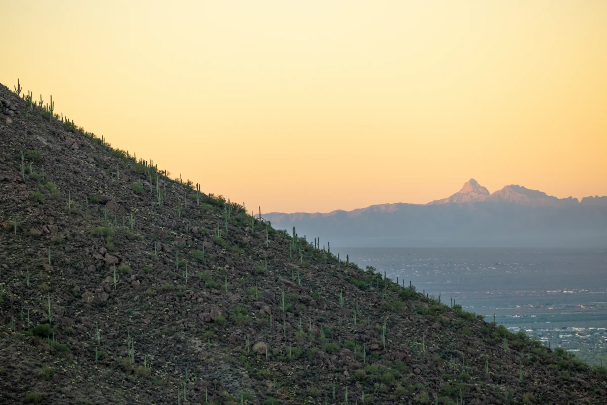 Desert mountain slope with distant peaks at sunset