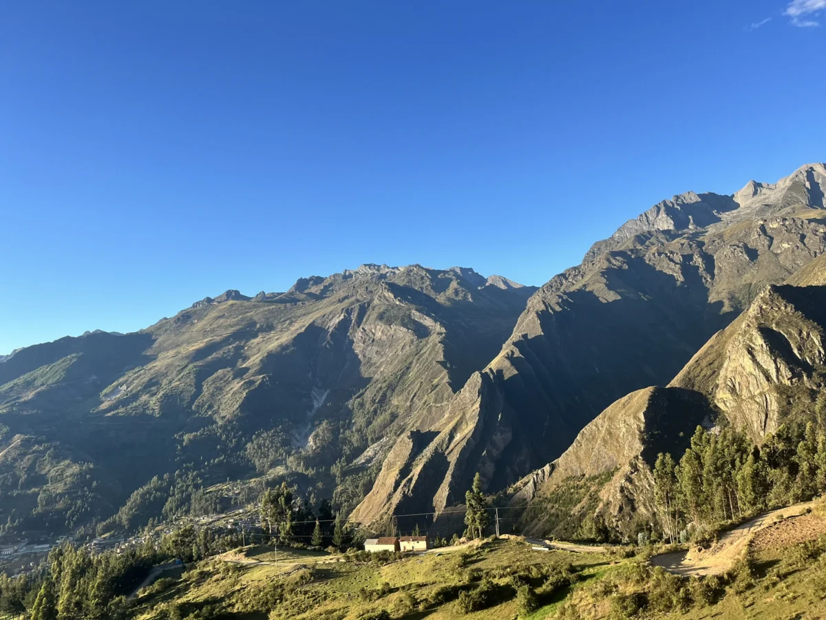 Sunlit mountains with scattered trees and buildings.