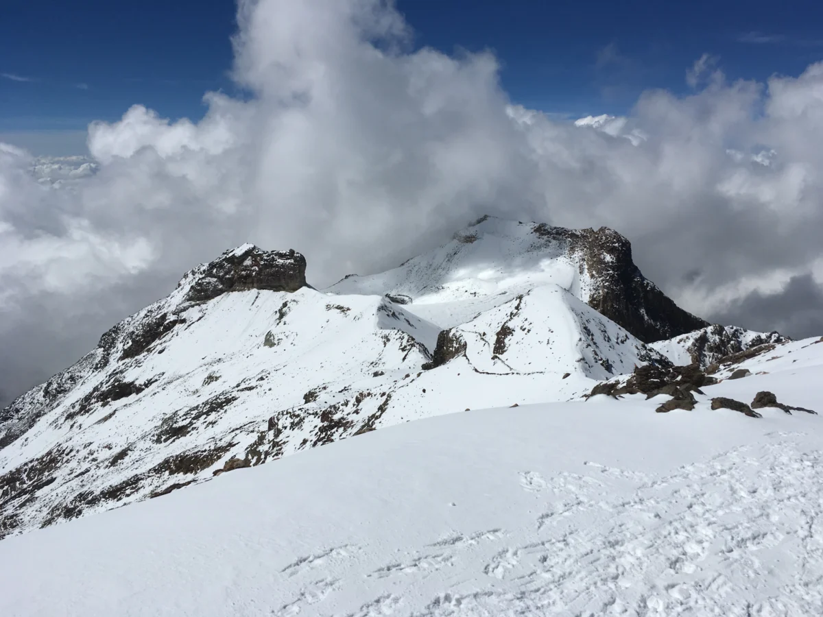 a snowy mountain with clouds