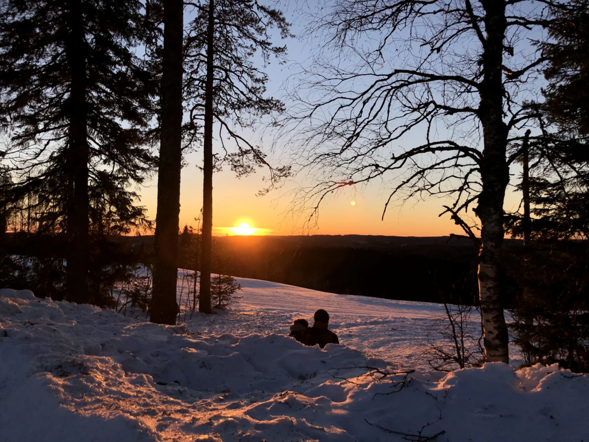 a person sitting in the snow at sunset