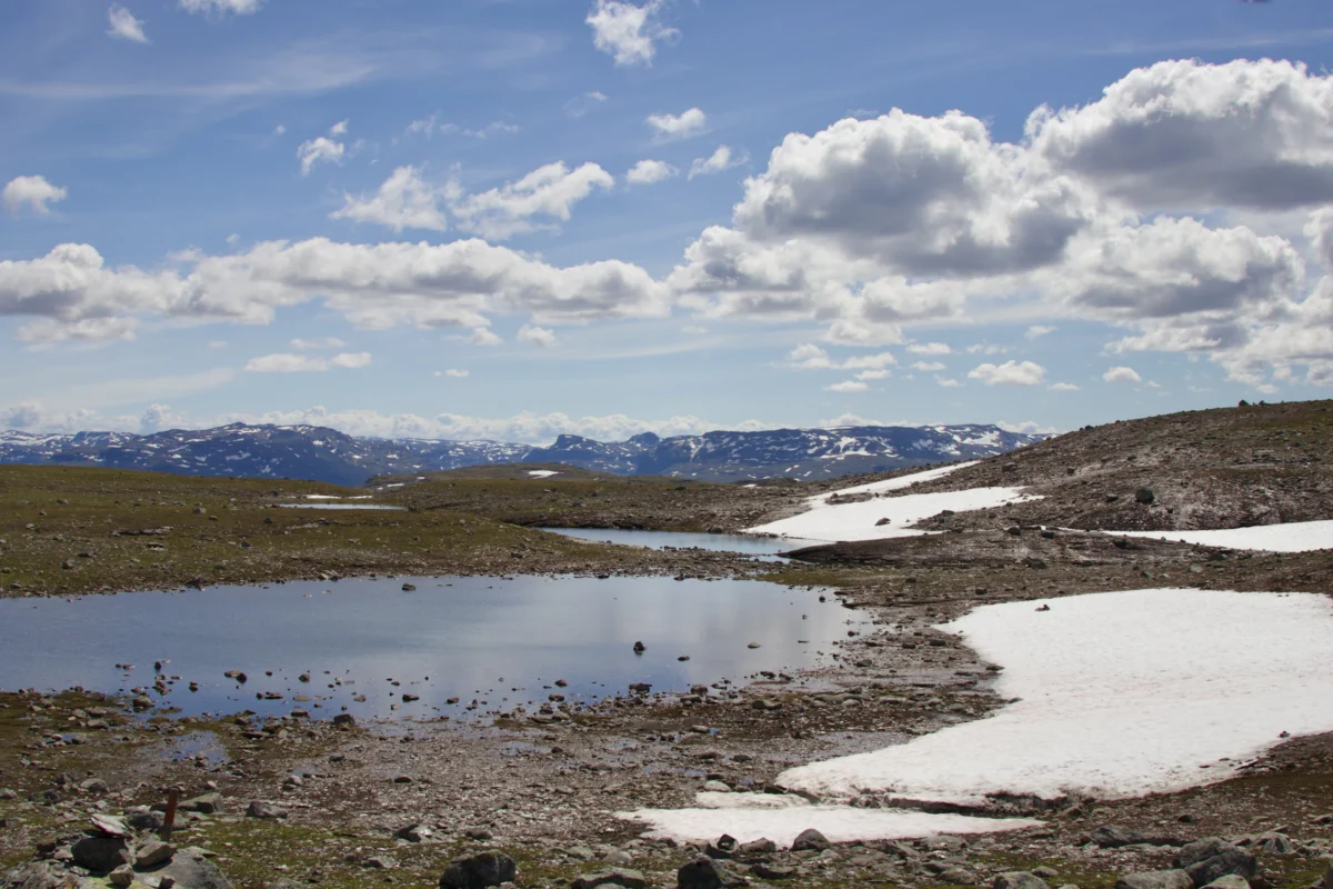 a lake surrounded by snow covered mountains under a blue sky