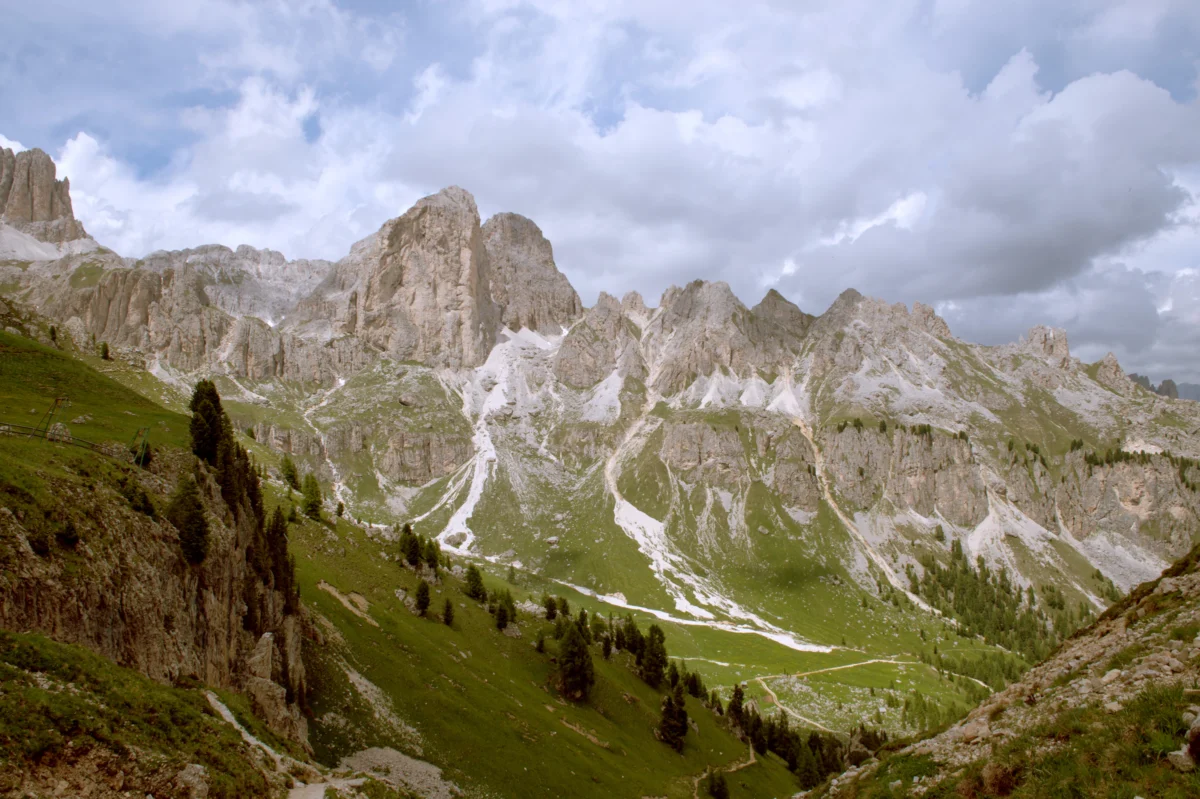 the mountains are covered in snow and green grass