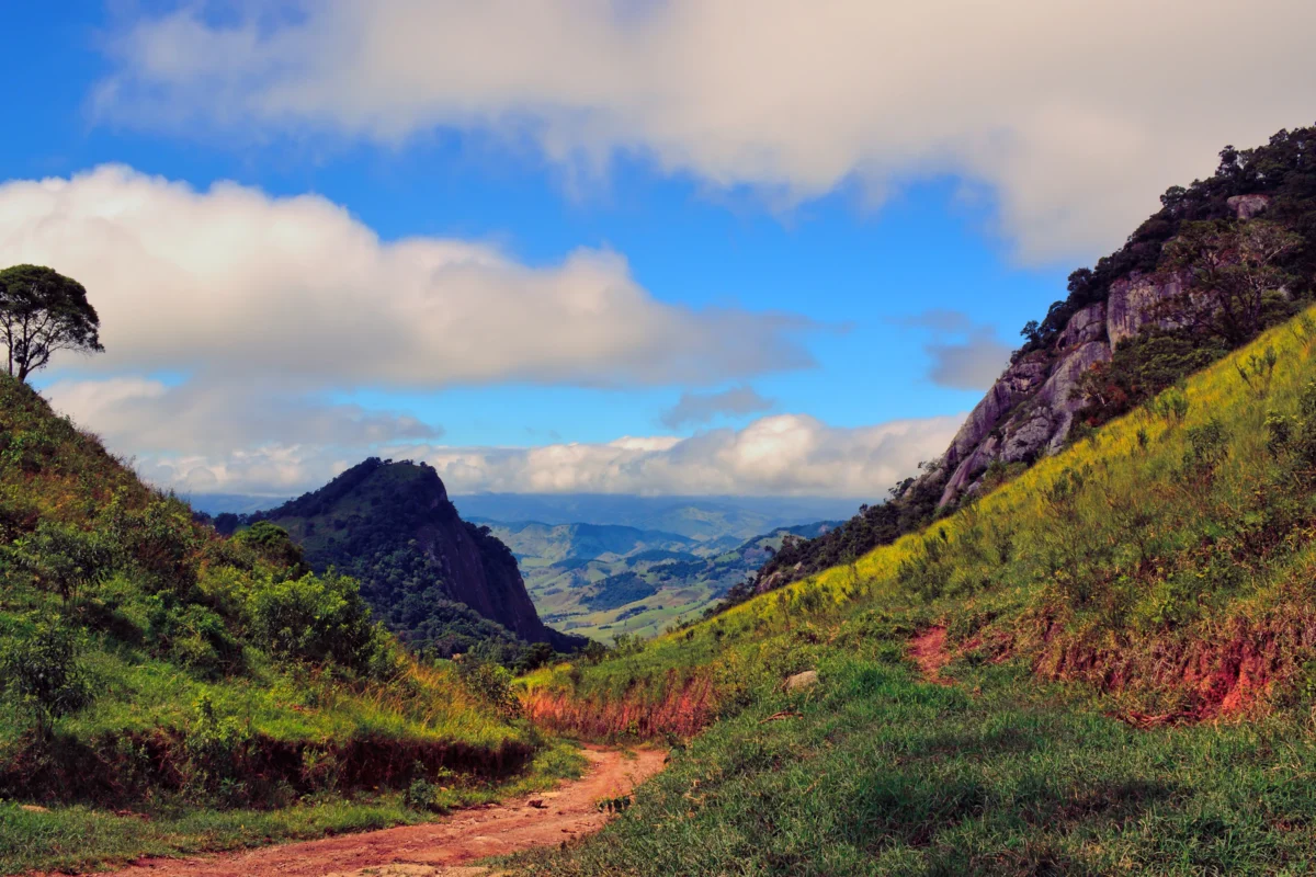 a dirt road going through a lush green valley