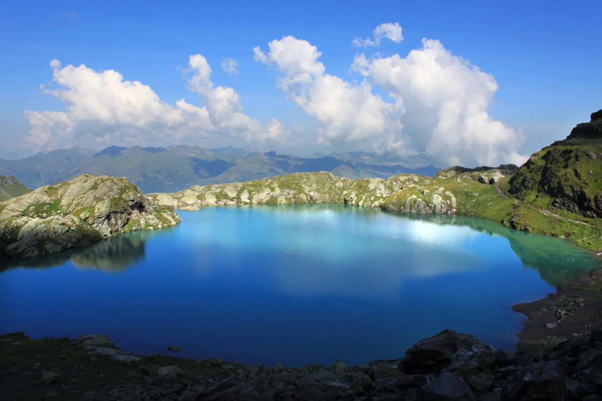 Turquoise lake surrounded by rocky, snow-capped mountains.