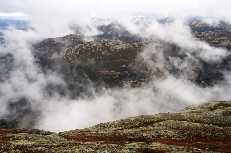 Misty clouds drift over a rugged, rocky landscape.