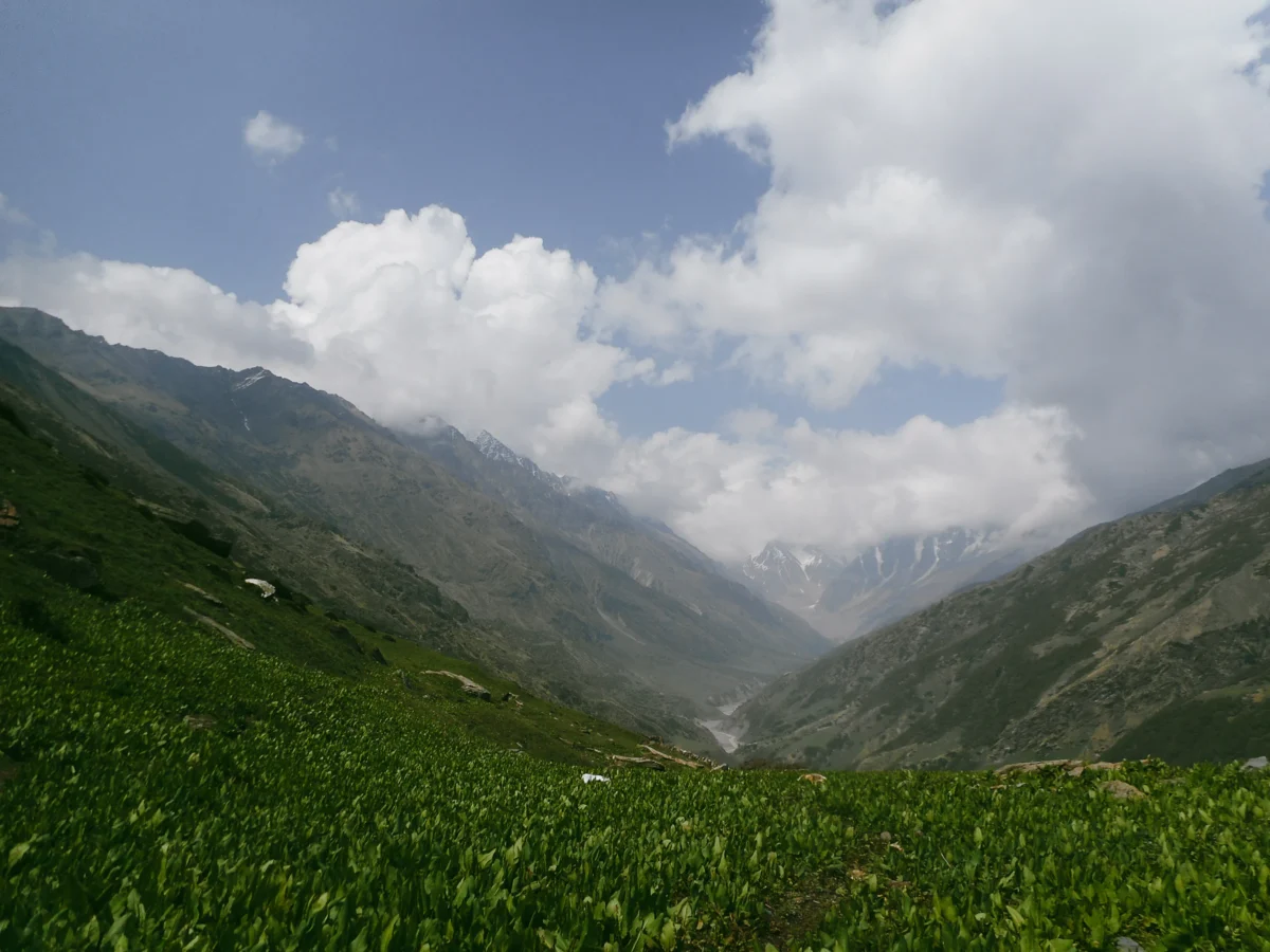 Green valley with mountains and clouds under blue sky