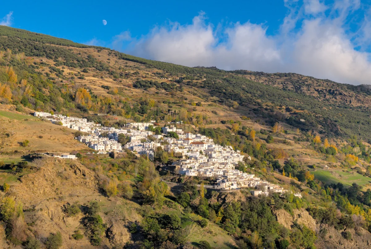 Hills and mountains stretch beneath a bright blue sky.
