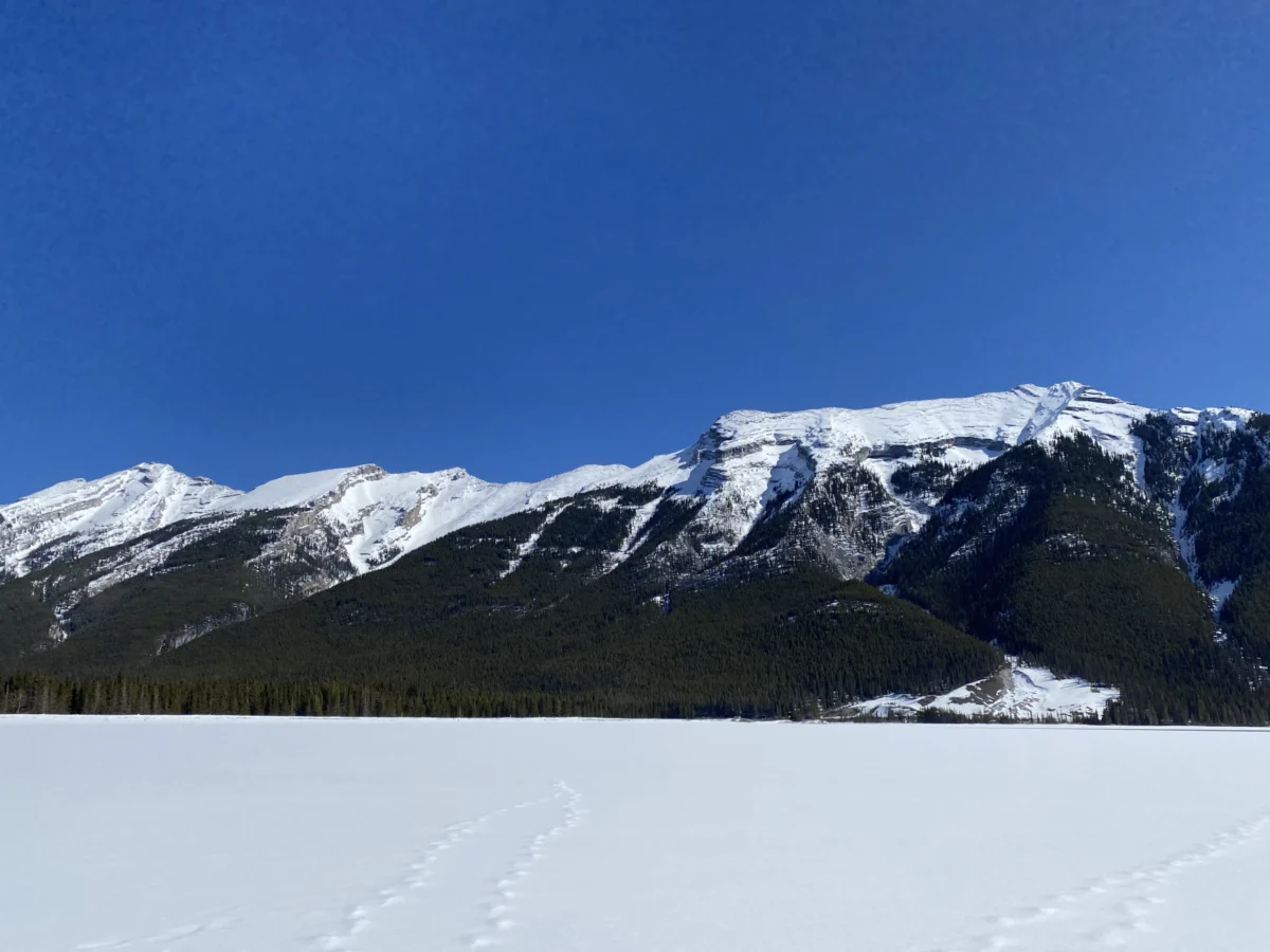 A person on skis in the snow with mountains in the background