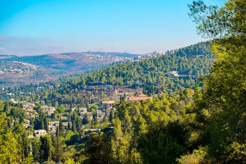 Green hills with scattered buildings under a clear blue sky.