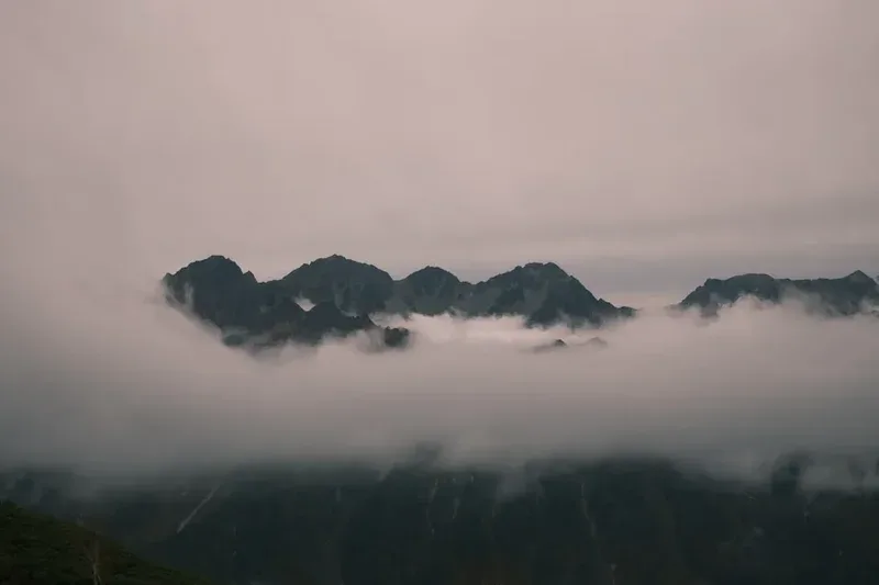 Misty mountains emerge from thick fog.