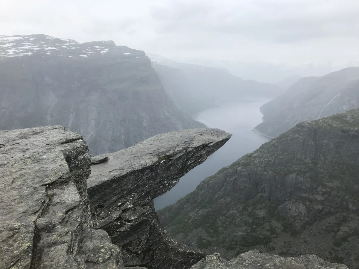 person at a gray cliff overlooking a river