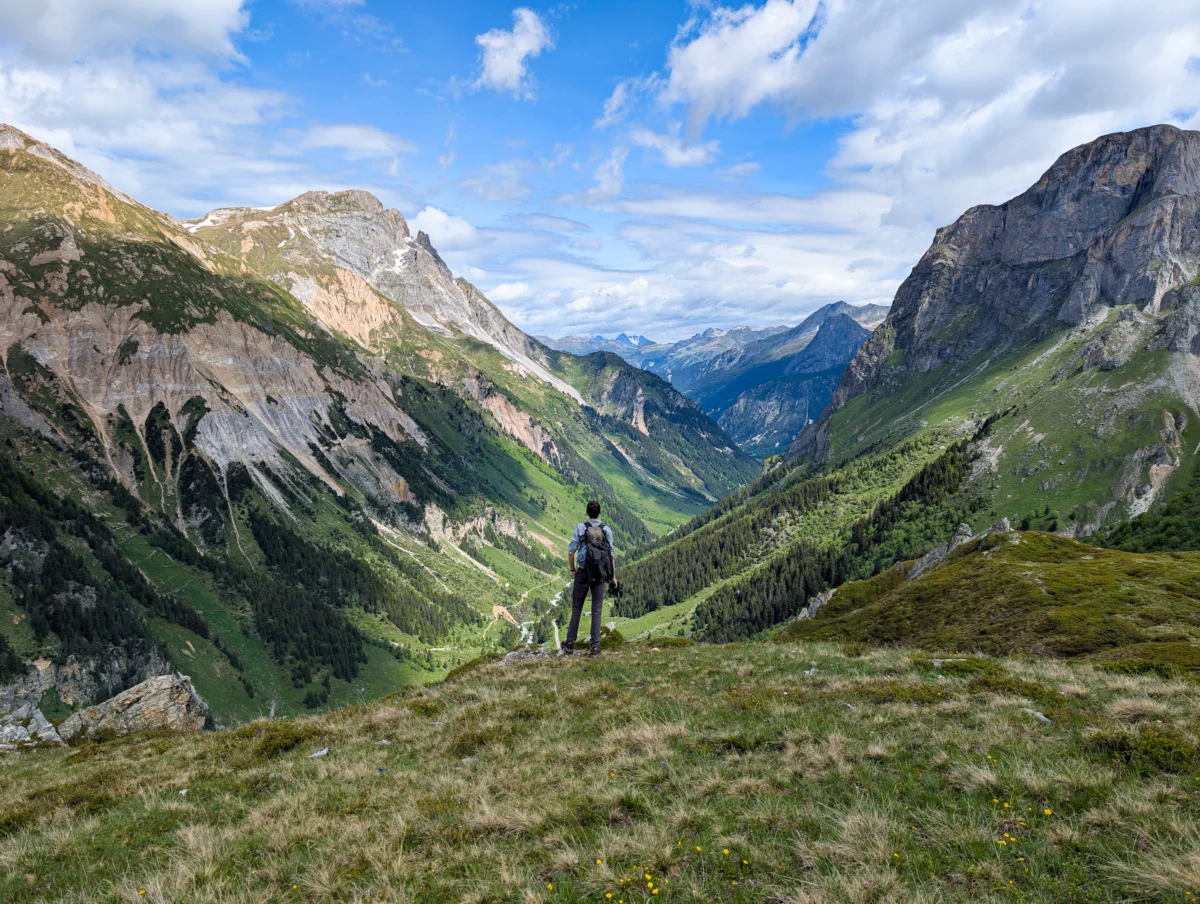 A hiker stands, taking in a mountainous vista.