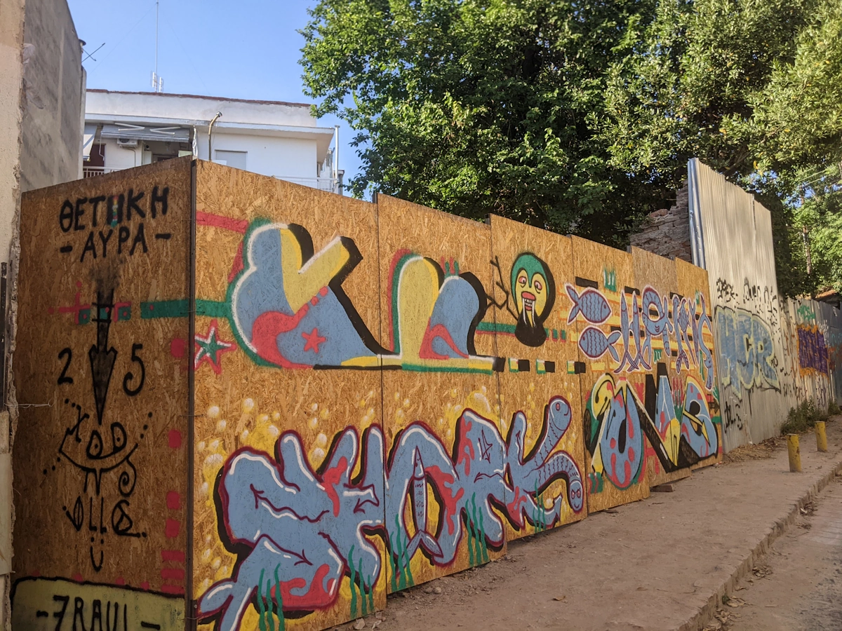 Large outdoor graffiti wall with colourful character lettering on plywood boards, Thessaloniki