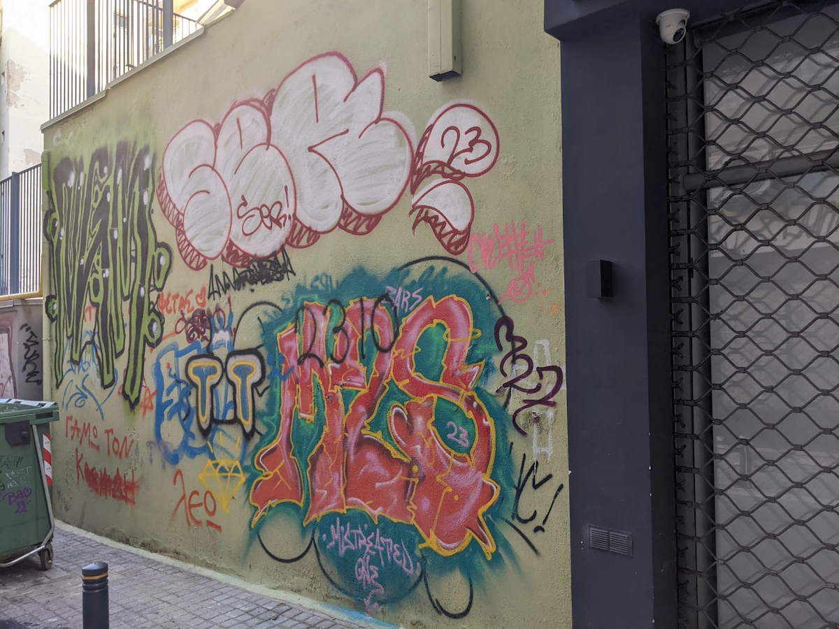 Yellow wall covered in overlapping graffiti throw-ups and tags, Thessaloniki