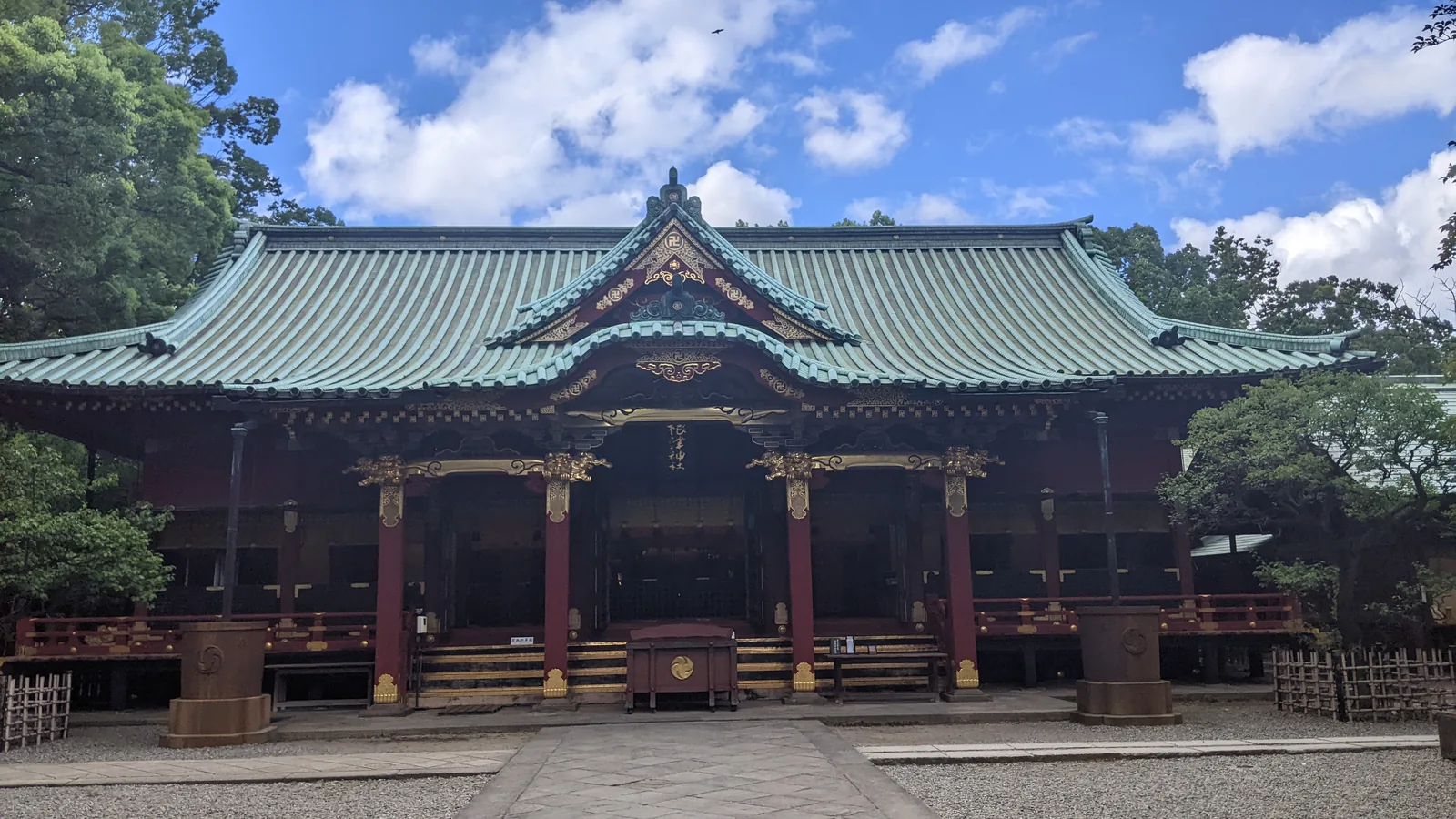 Green-roofed temple hall with ornate eaves set against a blue sky in Tokyo