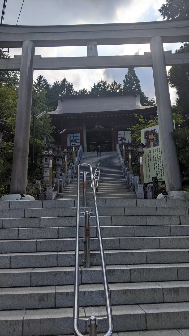 Stone torii gate at the foot of a long staircase climbing to a shrine in Tokyo