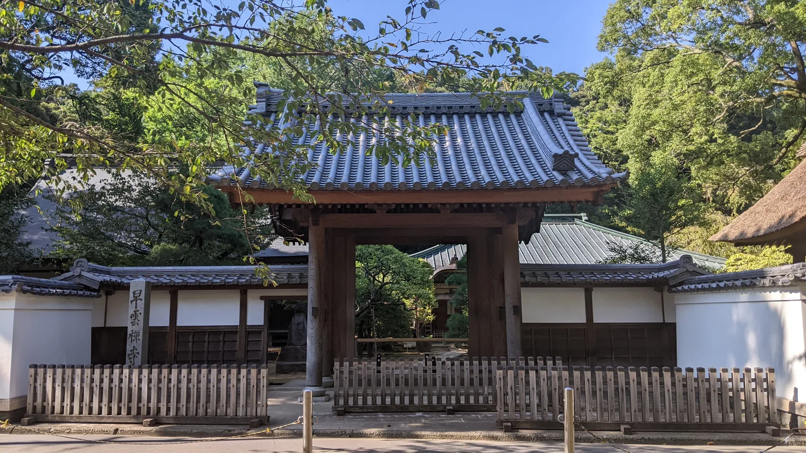 Traditional temple gate with tiled roof framed by green trees in Tokyo