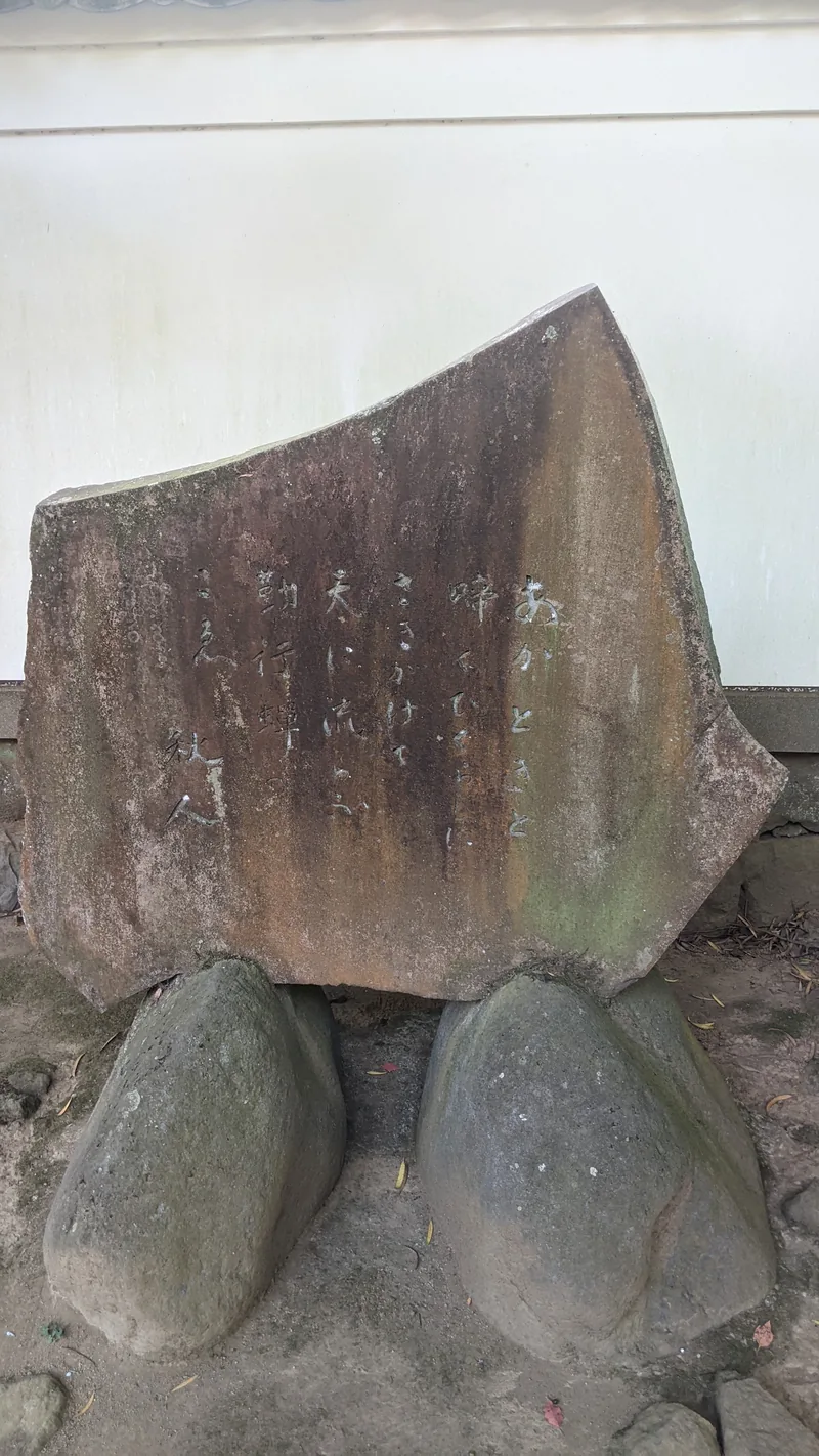 Large natural stone monument resting on rounded boulders at a Tokyo temple