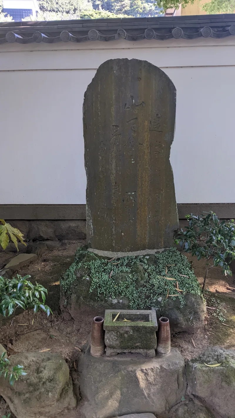 Carved stone stele monument set among greenery at a Tokyo temple