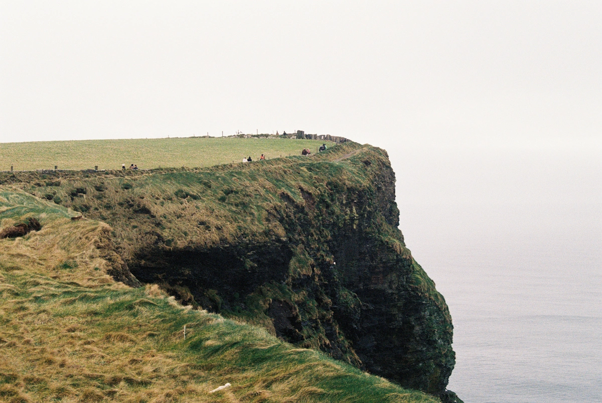 Majestic green grassy cliffs rising dramatically over the Atlantic Ocean at the Cliffs of Moher in County Clare, Ireland