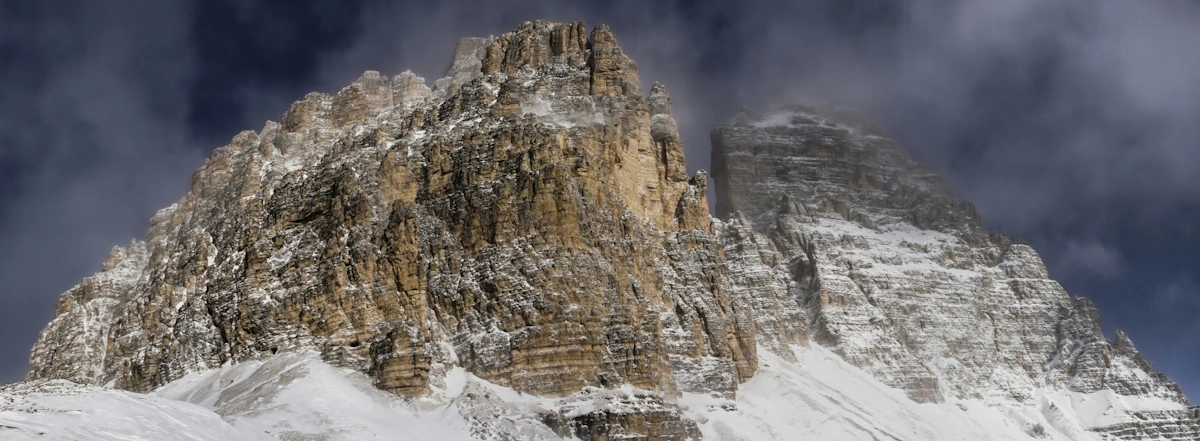 The dramatic jagged peaks of Tre Cime di Lavaredo rising sharply in the Dolomites with rocky alpine terrain