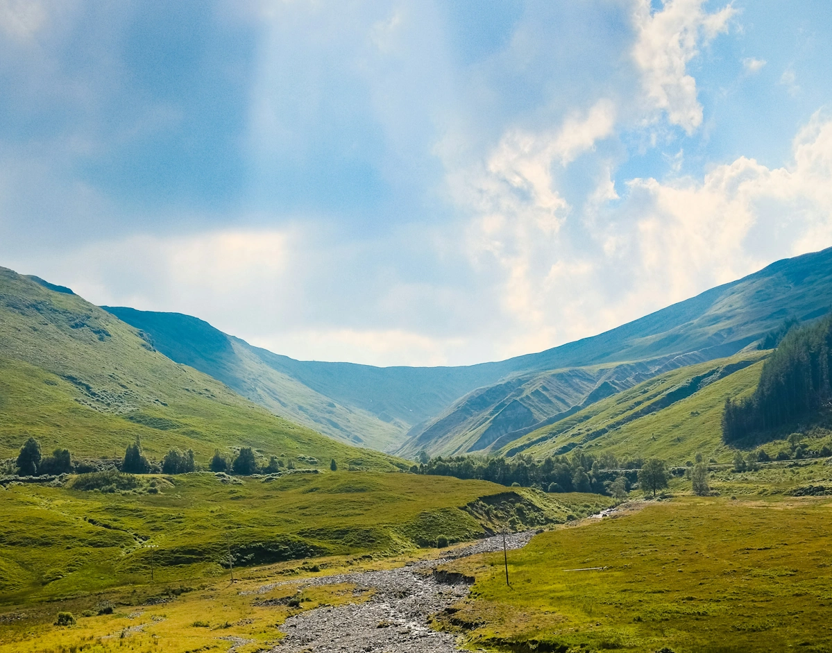 Green grass valley with winding trail through the dramatic Highland landscape of Glencoe on the West Highland Way