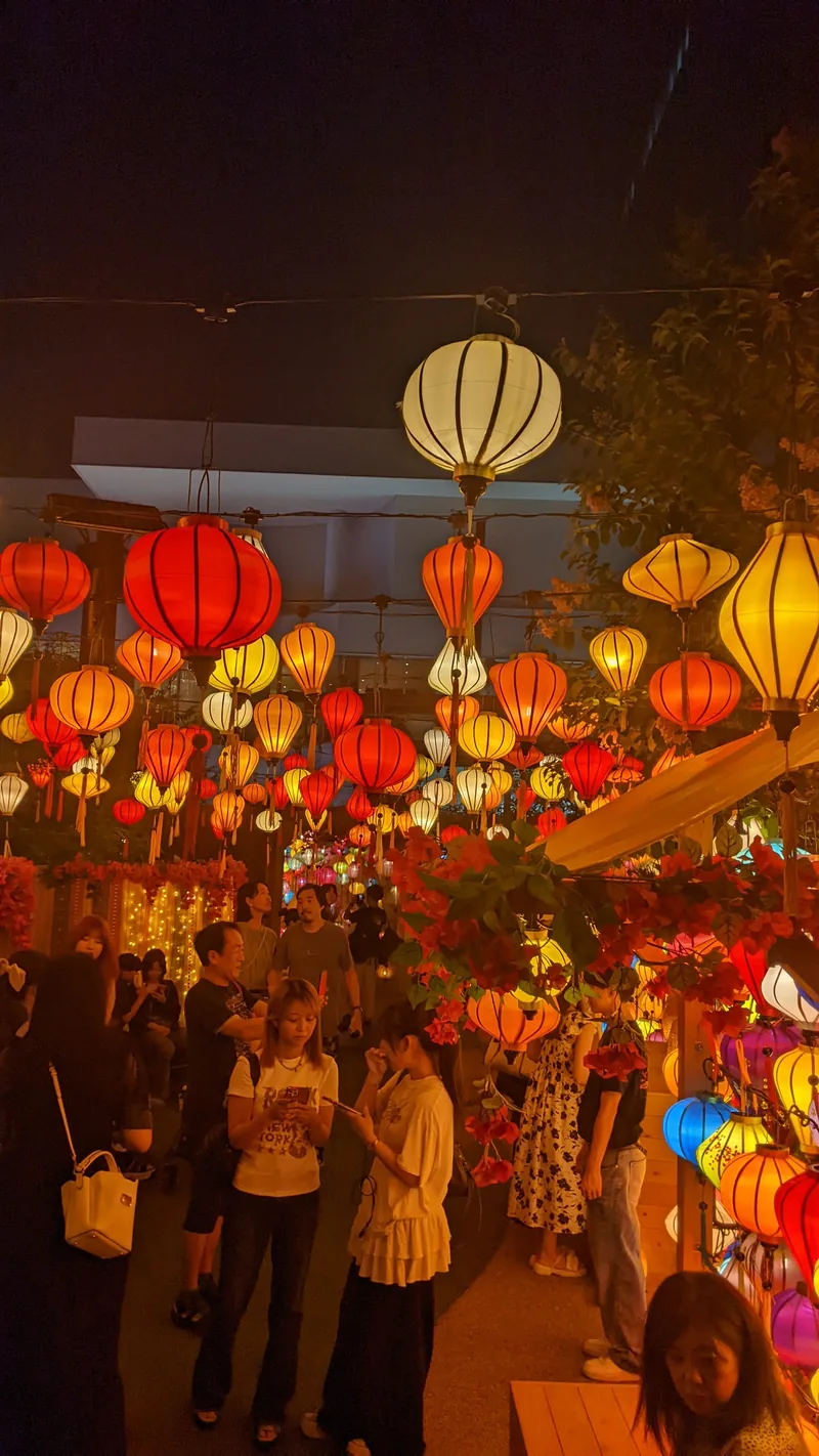 Crowd gathered beneath glowing red and gold lanterns at night in Yokohama