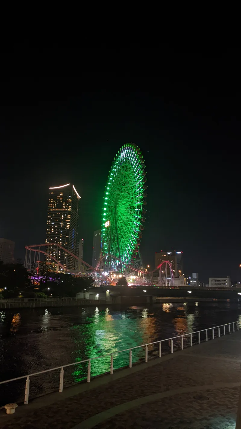The Cosmo Clock ferris wheel lit up over the water at night in Yokohama harbour